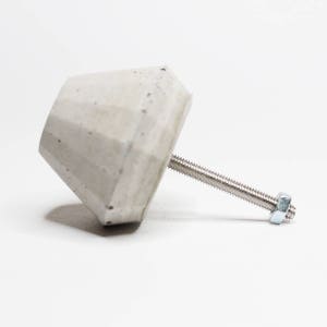 May include: A grey concrete cabinet knob with a silver screw and nut.