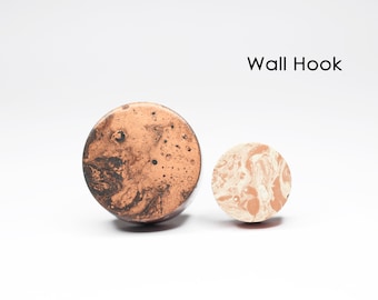 May include: Two round wall hooks with a marbled design. The larger hook is brown with black marbling, and the smaller hook is beige with white marbling. Wall Hook.