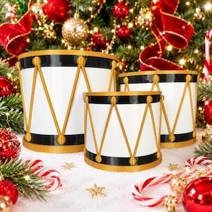 May include: Three cylindrical drum-shaped containers in varying sizes, featuring a white body with black horizontal bands at the top and bottom, accented by gold-colored vertical zig-zag trim and circular studs around the exterior.