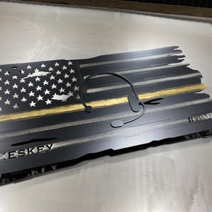 May include: A black and gold metal American flag with a thin yellow line, a headset, and the text "KESKEY #807".