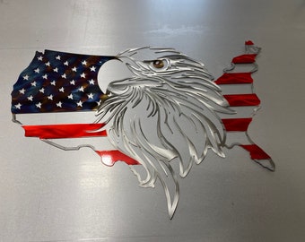May include: Metal wall art depicting an American bald eagle and the United States flag. The eagle is silver with a brown eye, and the flag features red and white stripes and blue with white stars. The artwork is in the shape of the United States.