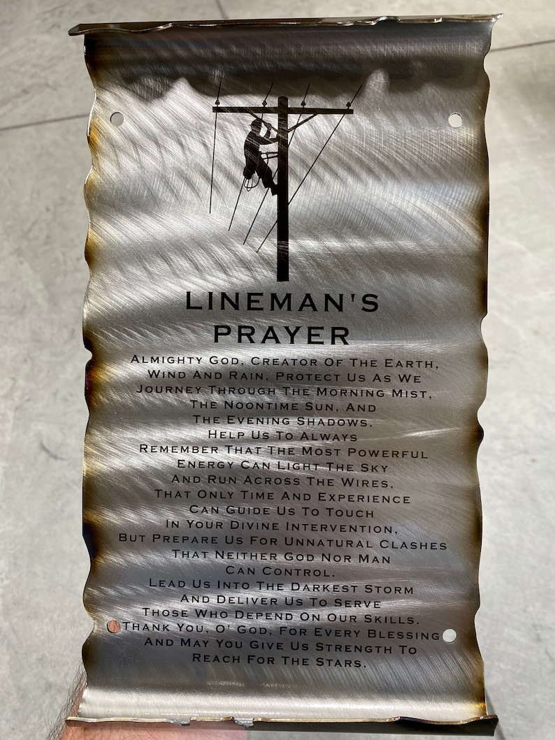 May include: A metal sign with a weathered, brushed finish features a silhouette of a lineman working on a power line. The sign includes a prayer for linemen, asking for protection and strength. The text reads: "Lineman's Prayer. Almighty God, Creator of the Earth, Wind and Rain, Protect us as we journey through the morning mist, the noontime sun, and the evening shadows. Help us to always remember that the most powerful energy can light the sky and run across the wires. That only time and experience can guide us to touch in your divine intervention, but prepare us for unnatural clashes that neither God nor man can control. Lead us into the darkest storm and deliver us to serve those who depend on our skills. Thank you, O' God, for every blessing and may you give us strength to reach for the stars."
