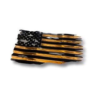 May include: A metal wall art piece depicting a distressed American flag. The flag features black and gold stripes with a black field of stars. The edges are torn, giving it a weathered appearance.
