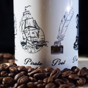 May include: White ceramic mug with black and white illustrations of a ship, a quill pen, and a chess piece. The mug has the words "Pirate", "Poet", and "Pawn" written on it. The mug is sitting on a surface with coffee beans scattered around it.
