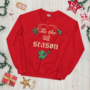 May include: Red Christmas sweatshirt with the text "Tis the mf season" in gold lettering and a green holly design.