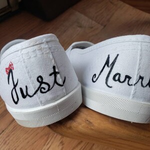 May include: A pair of white canvas shoes with black embroidery. One shoe says "Just" with a red and white polka dot bow. The other shoe says "Married" with a Mickey Mouse silhouette.