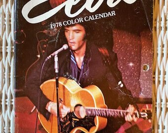 May include: A vintage 1978 Elvis color calendar featuring a photograph of Elvis Presley playing a guitar on stage. The calendar cover has the word "Elvis" in large white letters.
