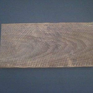 May include: A close-up of a light brown wooden plank with a natural wood grain pattern.
