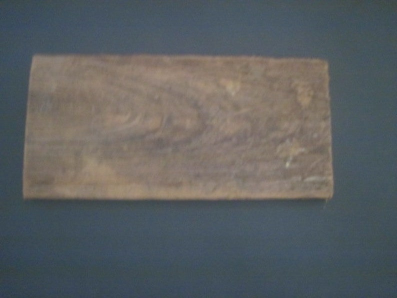 May include: A close-up of a piece of wood with a natural wood grain pattern. The wood is a light brown color with some darker brown streaks.