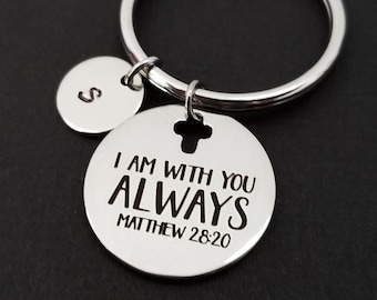 May include: Silver keychain with a round charm that says "I am with you always Matthew 28:20". The charm has a small cross cut out of it. There is a smaller round charm with the letter "S" on it.