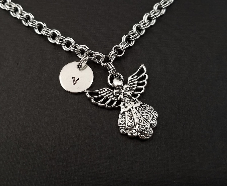 Peut inclure: Un collier en cha&icirc;ne argent avec un pendentif ange en argent et un pendentif rond en argent grav&eacute; de la lettre "V".