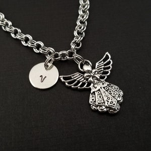 Peut inclure: Un collier en cha&icirc;ne argent avec un pendentif ange en argent et un pendentif rond en argent grav&eacute; de la lettre V.