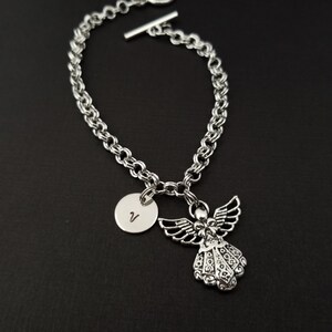 Peut inclure: Bracelet en cha&icirc;ne argent avec un charme ange en argent et un charme disque en argent grav&eacute; de la lettre V.