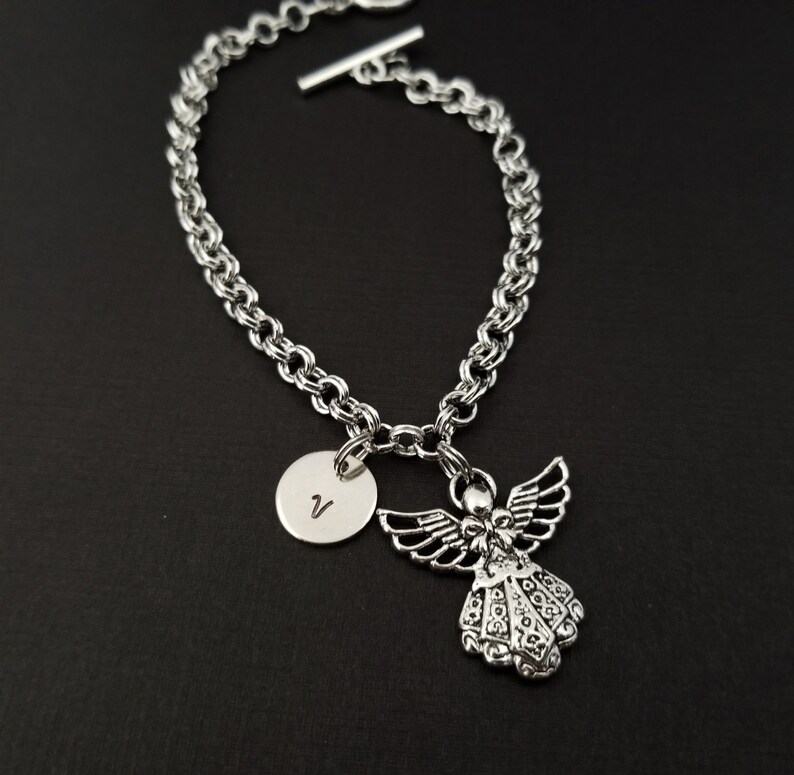 Peut inclure: Bracelet en cha&icirc;ne argent avec un charme ange en argent et un charme disque en argent grav&eacute; de la lettre V.