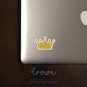 May include: A gold glitter crown sticker on a silver laptop. The sticker is about 2 inches wide.
