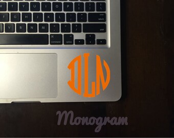 May include: A close-up of a laptop with an orange monogram sticker on the trackpad. The sticker is a circle with the letters "DLN" inside. The text "Monogram" is printed below the sticker.