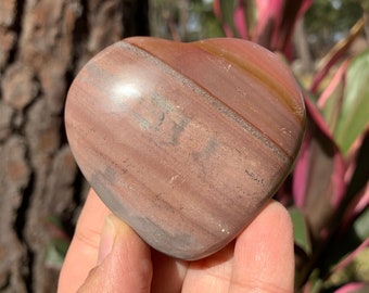 May include: A heart-shaped polished stone with brown, red, and gray stripes.