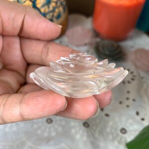 May include: A clear quartz crystal carved into the shape of a rose. The rose is detailed with delicate petals and is a beautiful example of crystal carving.