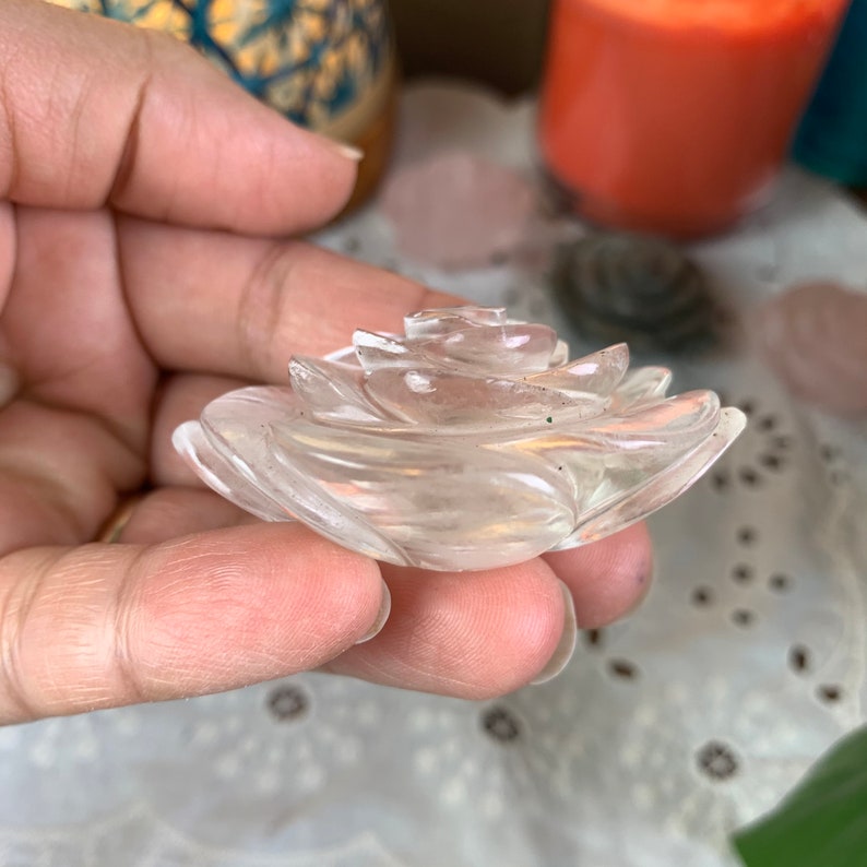 May include: A clear quartz crystal carved into the shape of a rose. The rose is detailed with delicate petals and is a beautiful example of crystal carving.