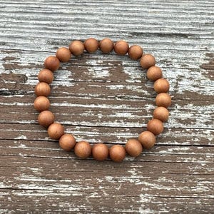 May include: A brown wooden beaded bracelet in a circular shape.