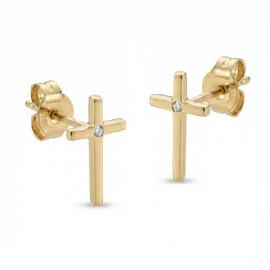 May include: A pair of gold-colored cross stud earrings. Each earring features a small, clear gemstone at the center of the cross. The earrings are displayed against a white background.
