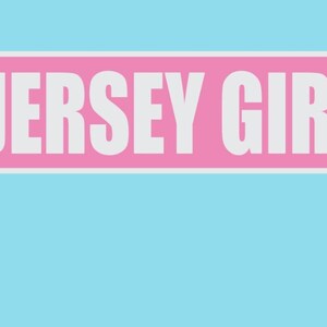 May include: A pink street sign with white text that reads "JERSEY GIRL LN". The sign is attached to a gray metal pole.