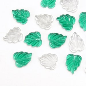 Op de afbeelding: Assortiment van groene en heldere glazen bladeren. Deze decoratieve bladeren zijn perfect om een ​​natuurlijke touch toe te voegen aan knutselwerk en projecten.