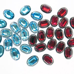 May include: Assortment of blue and red faceted glass gems. The gems are oval shaped and have a shiny finish.