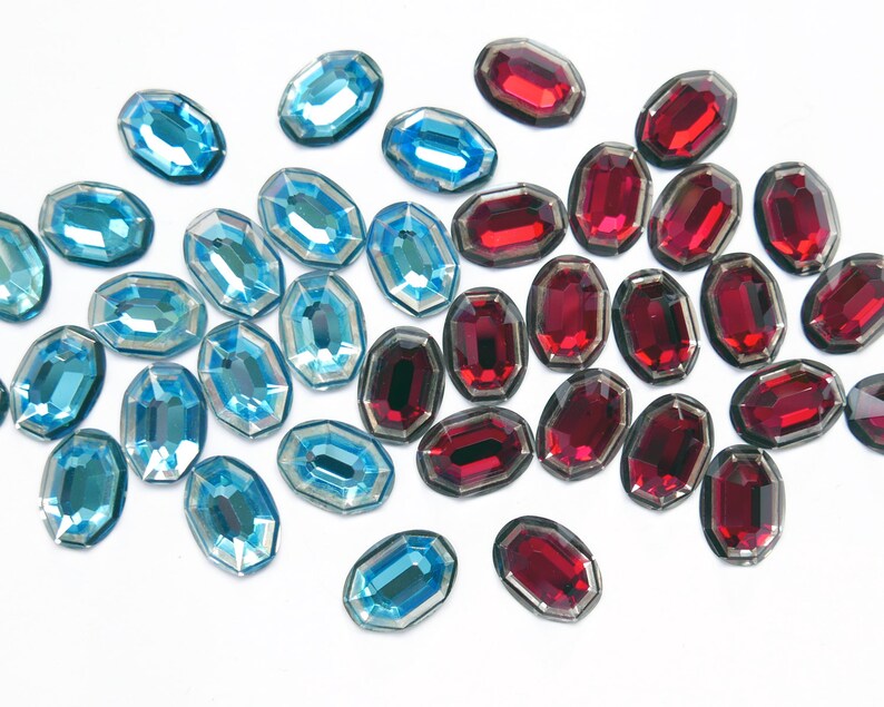 May include: Assortment of blue and red faceted glass gems. The gems are oval shaped and have a shiny finish.
