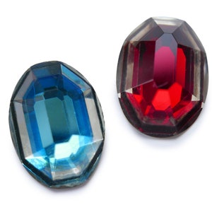 May include: Two faceted glass gems, one red and one blue, on a white background.