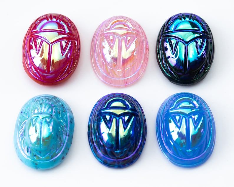 May include: Six iridescent glass scarab beetle charms in various colors, including red, pink, blue, and teal.