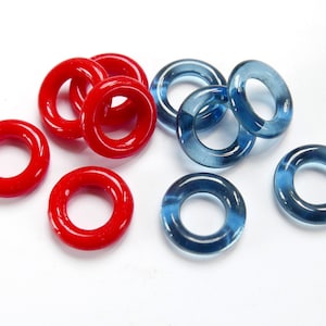 May include: A collection of red and blue glass rings. The rings are all the same size and shape, but they are different colours. They are perfect for making jewellery or crafts.