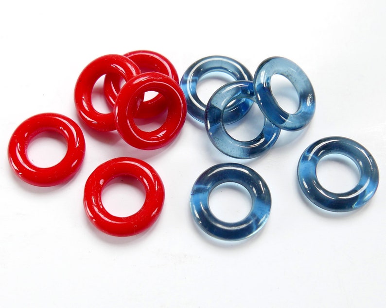 May include: A collection of red and blue glass rings. The rings are all the same size and shape, but they are different colours. They are perfect for making jewellery or crafts.