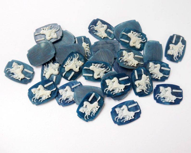 K&ouml;nnte beinhalten: Eine Sammlung von blauen und wei&szlig;en Keramikkn&ouml;pfen mit einem Design aus drei Pferden. Die Kn&ouml;pfe sind oval geformt und haben ein erhabenes Design.
