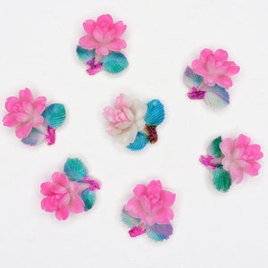 May include: Seven pink and white ceramic flower embellishments with blue and green painted leaves. The flowers have a 3D design and are perfect for adding a touch of whimsy to crafts.