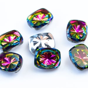Puede incluir: Surtido de botones de cristal iridiscente arcoíris con un diseño facetado. Los botones son de forma cuadrada y tienen un acabado brillante.