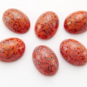 Könnte beinhalten: Sechs ovale Cabochons mit einem rot-weißen Marmormuster. Die Cabochons sind glatt und poliert.