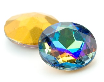 Puede incluir: Dos cabujones redondos facetados. Un cabujón presenta un acabado dorado mate sólido con una superficie geométrica de múltiples facetas. El otro cabujón muestra un acabado iridiscente vibrante con tonos cambiantes de azul, verde y morado.