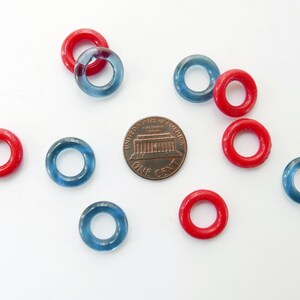 May include: A collection of red and blue plastic rings, similar to life preservers, with a US penny for scale.