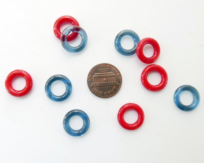 May include: A collection of red and blue plastic rings, similar to life preservers, with a US penny for scale.