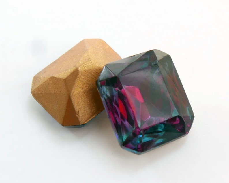 May include: Two faceted gemstones, one gold and one iridescent purple, green, and blue.