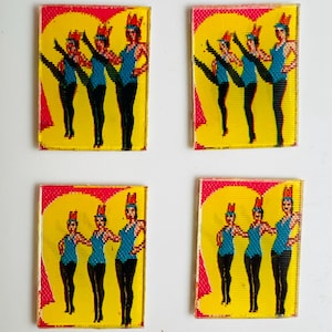 May include: Four rectangular glass art pieces featuring a yellow background with a red heart shape. Each piece depicts a group of three dancers in blue tops, black pants, and red headdresses. The dancers are in various poses.