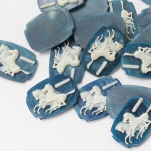 K&ouml;nnte beinhalten: Eine Sammlung von blauen und wei&szlig;en Keramikkn&ouml;pfen mit einem Design von drei galoppierenden Pferden. Die Kn&ouml;pfe sind oval geformt und haben eine glatte, gl&auml;nzende Oberfl&auml;che.