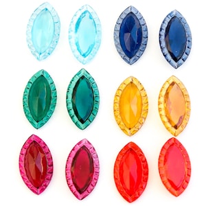 May include: Twelve colorful, faceted, teardrop-shaped glass gems with a scalloped edge. The gems are arranged in three rows of four, with each row featuring a different color: blue, green, yellow, red.