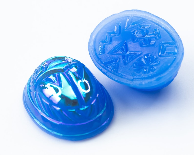 May include: Two blue glass scarab beetle charms, one with an iridescent finish and the other with a carved design.