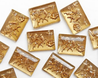 Puede incluir: Diez azulejos de vidrio en tono dorado con un diseño en relieve de pájaros y flores. Los azulejos son rectangulares y tienen una apariencia translúcida.