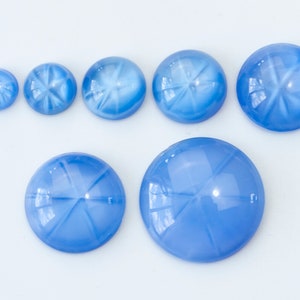 Puede incluir: Siete piedras preciosas cabujón redondas, azules en forma de estrella de diferentes tamaños.