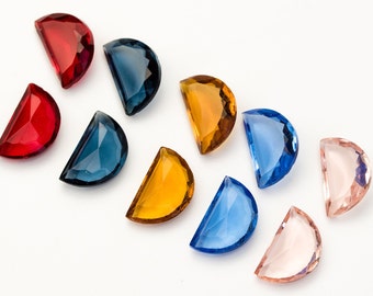 May include: Assortment of ten half-moon shaped glass gems in various colors, including red, blue, yellow, and pink. The gems are arranged in a semi-circle on a white background.