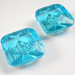 May include: Two square, light blue glass paperweights with an etched image of the Taj Mahal.