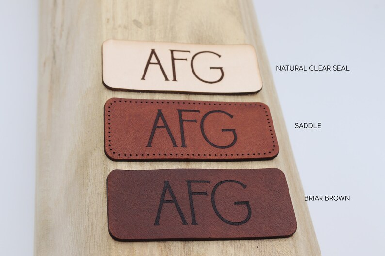 May include: Three leather patches with the initials "AFG" embossed in black. The patches are in three different colors: natural clear seal, saddle, and briar brown.